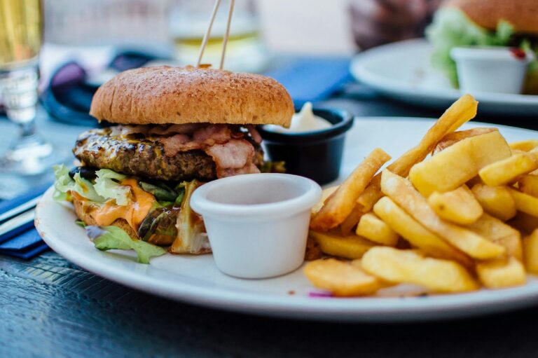 Comida 1 Close-up of a juicy burger and crispy fries served with sauces, perfect for a hearty meal.